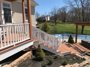 Composite Deck - Trex Transcends "Tiki Torch" with white vinyl railings  leading to swimming pool in Coopersburg, PA.