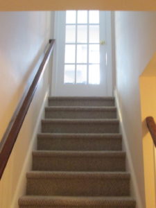 A carpeted stair case leading to finished basement