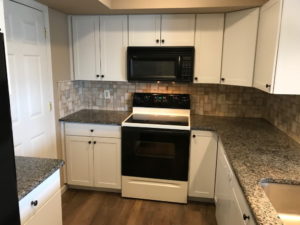 Kitchen Renovation - Cream melamine finish cabinets with granite counter top with rustic laminate floor located in Quakertown, PA.
