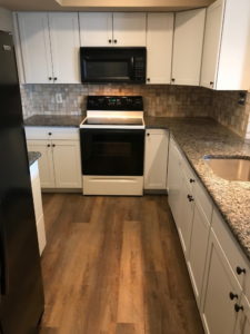 Kitchen Renovation - Cream melamine finish cabinets with granite counter top with rustic laminate floor in Quakertown, PA.