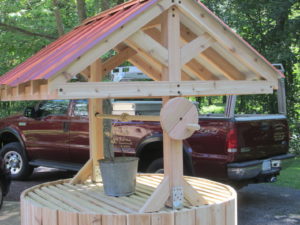 This custom cedar wishing well with a red metal roof  was built to hide an electrical Utility box in Bedminster.